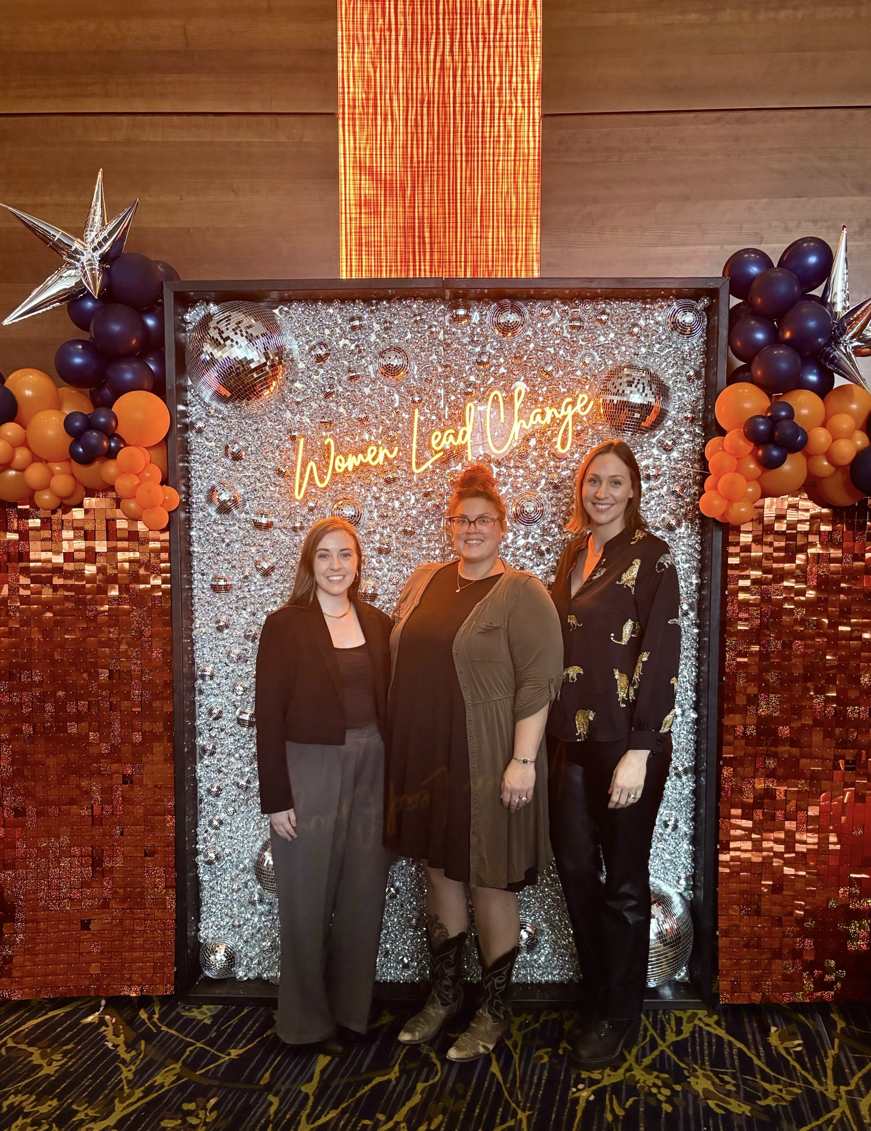 From left, Alecia Kindred, Holly Murphy and Stacey Myers of Visionary Services at the Women Lead Change photo wall